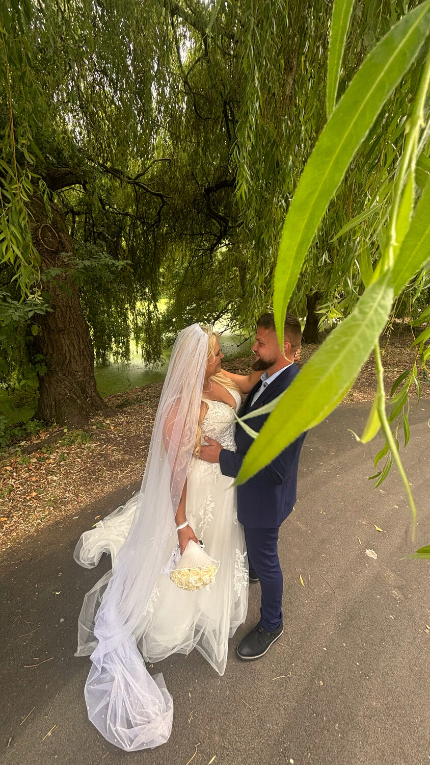 Full-body photo of the bride and groom under the willow tree